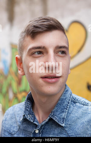 Portrait d'un adolescent homme rebelle sur un mur de graffiti background Banque D'Images