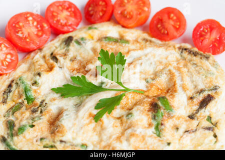 Omelette aux asperges juteuses entouré de petites tomates Banque D'Images