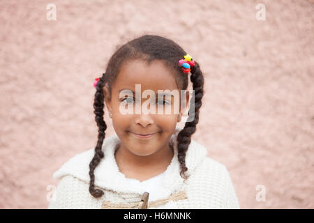 Belle enfant africain avec une brique d'un mur rose de l'arrière-plan Banque D'Images