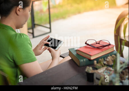 Scène de vie matin de jeunes hipster woman using mobile phone alors qu'il était assis sur un banc en bois. avec tec numérique Banque D'Images