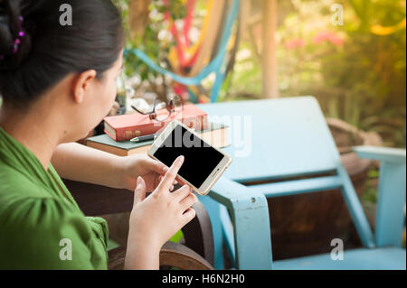 Scène de vie matin de jeunes hipster woman using mobile phone alors qu'il était assis sur un banc en bois. avec tec numérique Banque D'Images