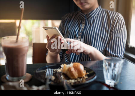 Scène de vie dimanche matin de jeunes hipster woman using mobile phone while sitting in cafe. Sur un week-end avec