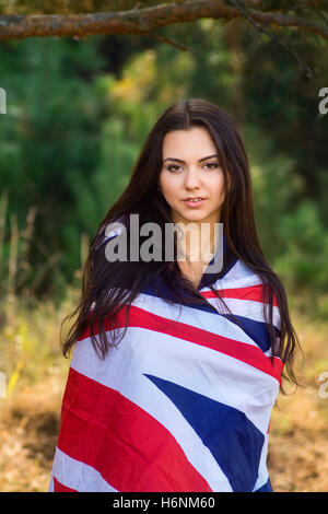 Belle jeune fille brune posant avec un drapeau britannique dans la région de autumn park Banque D'Images