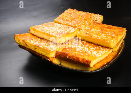 Tranche de gâteau au fromage avec graines de sésame sur un fond noir Banque D'Images