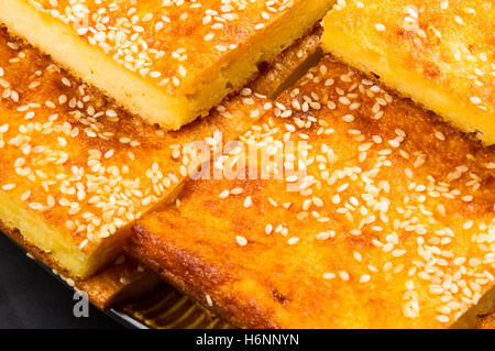 Tranche de gâteau au fromage avec graines de sésame sur un fond noir Banque D'Images