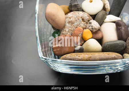 Galets décoratifs multicolores dans des contenants en verre sur fond noir Banque D'Images