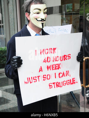 Un activist holding un écriteau "Je travaille 40 heures par semaine pour que je puisse lutter' à une manifestation de grand sauvetage des banques. Banque D'Images