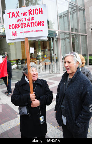 Un activist holding un écriteau "taxer les riches et leurs entreprises' à une protestation de grandes banques, pour protester contre le plan de sauvetage bancaire. Banque D'Images