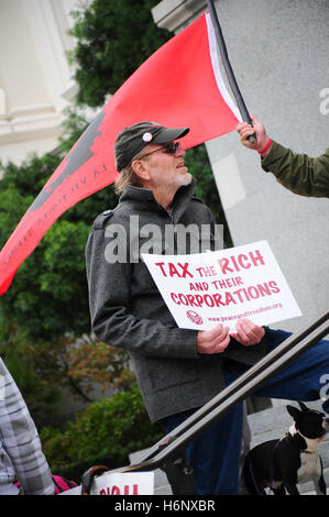 Un activist holding un écriteau "taxer les riches et leurs entreprises' à une protestation de grandes banques, pour protester contre le plan de sauvetage bancaire. Banque D'Images