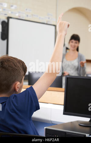 Élève de sexe masculin en répondant à la question de classe de l'école Banque D'Images