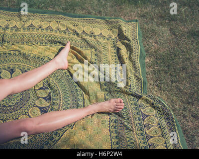 Les jambes d'une jeune femme comme elle est relaxant à l'extérieur sur l'herbe Banque D'Images