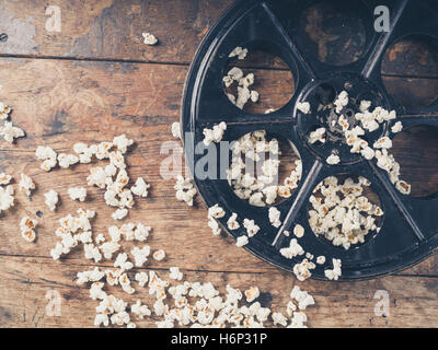 Concept de cinéma vintage bobine de film avec pop-corn sur la surface en bois Banque D'Images