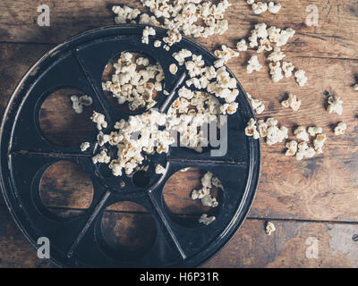 Concept de cinéma vintage bobine de film avec pop-corn sur la surface en bois Banque D'Images