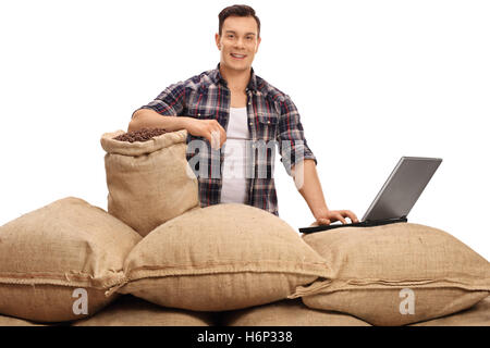 Les jeunes travailleurs agricoles posant avec sacs de toile remplis de grains de café et un ordinateur portable isolé sur fond blanc Banque D'Images