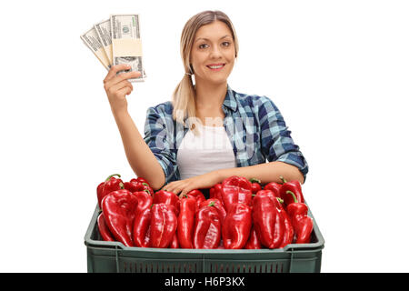 La productrice qui posent avec une caisse pleine de piment et de l'argent offres packagées isolé sur fond blanc Banque D'Images