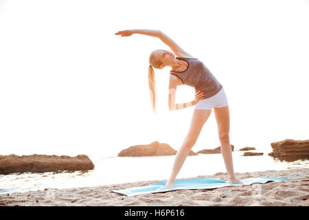 Belle jeune femme mains étirement au cours de yoga sur la plage