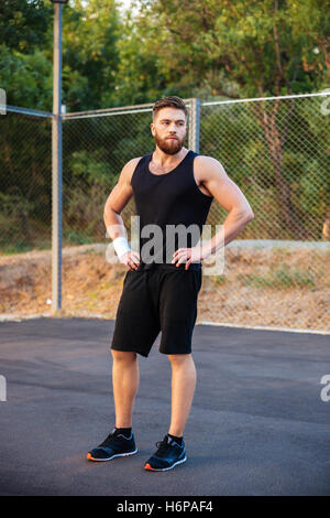 Jeune homme barbu en concentré sportswear standing outdoors Banque D'Images