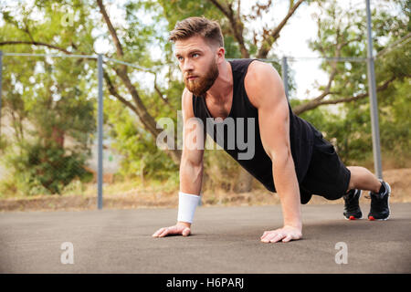 Les jeunes barbus attrayant sportsman faisant push-ups à l'extérieur Banque D'Images