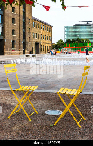 Deux chaises pliantes en métal jaune et noir et par les fontaines dans le grenier Square, King's Cross, Londres, Royaume-Uni, 2012 Banque D'Images