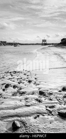 Image en noir et blanc de l'estran boueux de la Tamise à North Woolwich, Londres, Royaume-Uni, en amont, à l'embarcadère de ferry de Woolwich dans la distance Banque D'Images