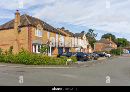 Rangée de maisons individuelles, construit en 1994, sur un lotissement, avec jardins avant ouvert pour le parking ; Northampton, Royaume-Uni Banque D'Images