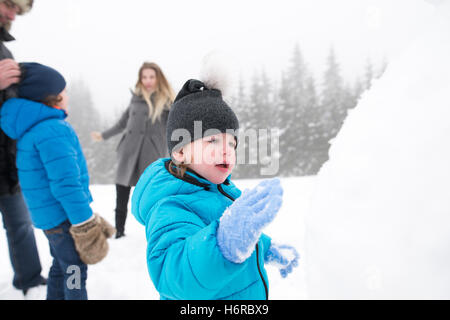 Les parents avec leur fils, jouer dans la neige, bonhomme de bâtiment. Banque D'Images