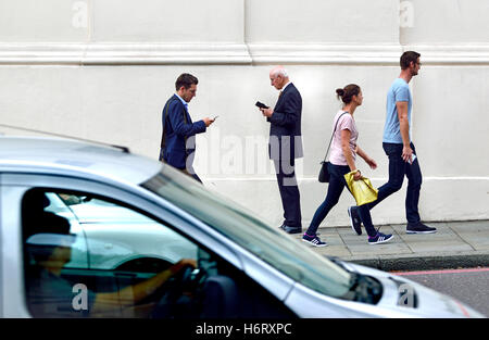 Londres, Angleterre, Royaume-Uni. Les personnes qui utilisent les téléphones mobiles, à Hyde Park Corner Banque D'Images