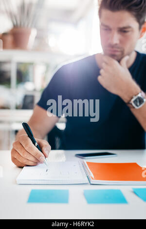 Portrait en bas de quelques remarques importantes dans office journal à son bureau au travail. Male executive écrit à titre personnel ou Banque D'Images