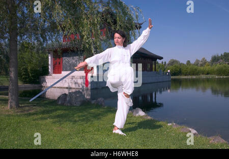 Femme, début de la quarantaine, faisant de Tai Chi avec une épée dans un jardin chinois à Berlin Banque D'Images