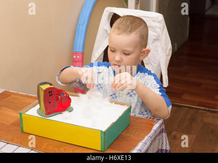 Boy in striped shirt assis à la table et de faire de l'artisanat Banque D'Images