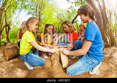 Heureux les enfants qui jouent avec des rondins dans la forêt Banque D'Images