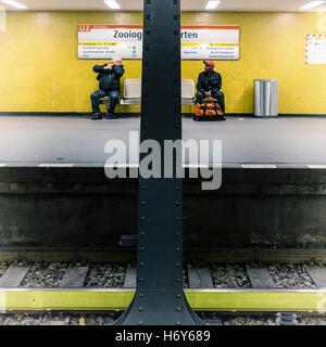 Deux hommes assis sur un banc sur la plate-forme en attente de train au jardin zoologique, la station de métro Zoologischer Garten Ubahn Banque D'Images