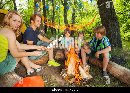 Grande famille heureuse griller des guimauves sur un bois Banque D'Images