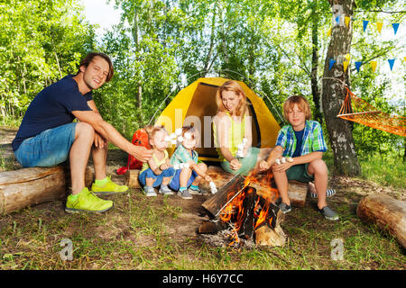 Famille heureuse griller des guimauves sur un bois Banque D'Images