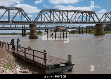 Les hommes la pêche comme restauré paddlesteamer passe sous les ponts routiers et ferroviaires sur la rivière Murray à Murray Bridge, dans le sud de l'Australie Banque D'Images