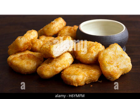 Pile de golden deep-fried chicken nuggets battues avec bol rustique vide sur le bois sombre. Une coupe avec de la viande. Banque D'Images