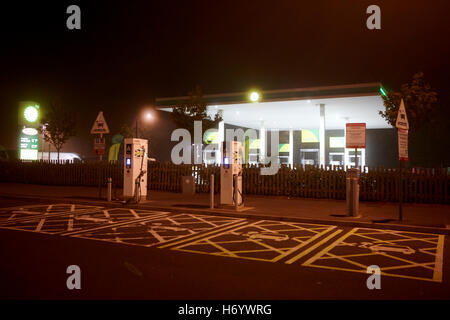 Les services d'autoroute bp station service carburant avec des points de recharge pour voitures électriques dans le brouillard pendant la nuit United Kingdom Banque D'Images