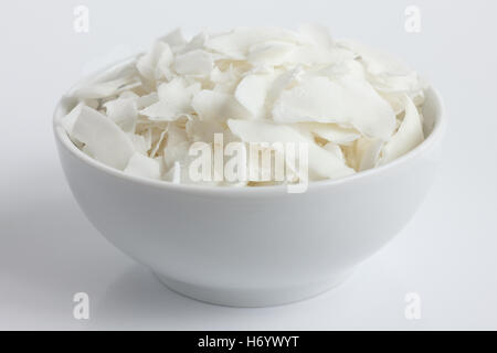 Flocons de noix de coco dans un bol en céramique blanche. En perspective. Banque D'Images