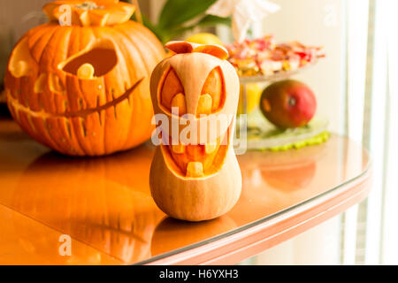 Smiling Halloween Orange tête de citrouille sur une table avec un fond de citrouille et candy rack. Banque D'Images