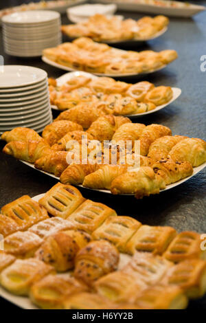 Des croissants et autres viennoiseries disposés sur des plateaux blanc sur une surface noire avec plaques Banque D'Images