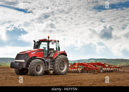 Tracteur rouge moderne dans le domaine de l'agriculture. Banque D'Images