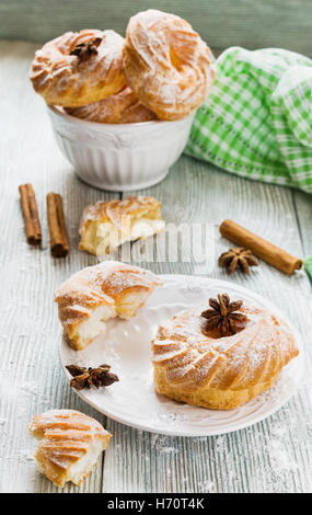 Les gâteaux ronds avec crème à la vanille et du sucre en poudre sur une table en bois, blanc vintage de la vaisselle. Banque D'Images