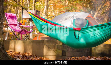 Un camping-dort dans un hamac suspendu comme le soleil du matin se lève sur le terrain de camping au parc d'état de Vogel près de Blairsville, GA. Banque D'Images