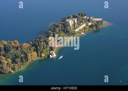 VUE AÉRIENNE. Île boisée à l'automne et une villa néo-gothique vénitienne. Isola del Garda, Lac de Garde, province de Brescia, Lombardie, Italie. Banque D'Images