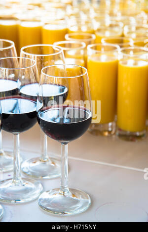 Verres de vin rouge et le jus d'orange à l'attente de l'événement à table Banque D'Images