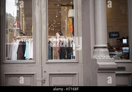 Les clients vu dans la fenêtre d'un magasin de vêtements américains à New York le samedi 29 octobre, 2016. American Apparel est signalé à être le dépôt pour le chapitre 11 de nouveau faillite après avoir émergé de sa première faillite en février. (© Richard B. Levine) Banque D'Images