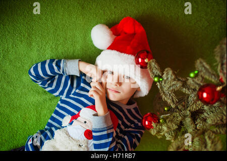 Petit garçon est située près de sapin. Les jours fériés. dans un T-shirt à rayures avec le Père Noël Banque D'Images