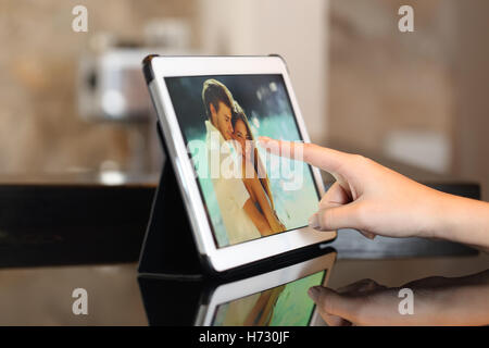 La main à l'aide d'une tablette en regardant des photos à la maison Banque D'Images