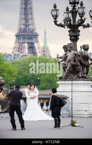 PARIS - le 19 mai 2013 : Asian Bride and Groom poser pour des photos sur le Pont Alexandre III pont avec une vue sur la Tour Eiffel. Banque D'Images