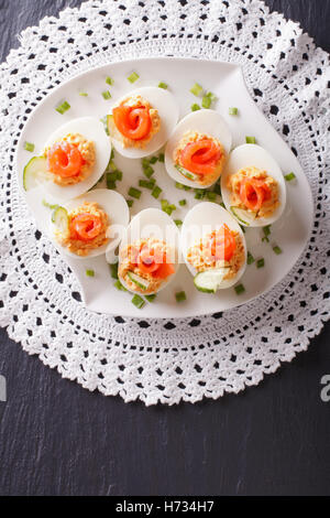 Oeufs farcis au saumon, concombre et fromage sur une table. vertical Vue de dessus Banque D'Images